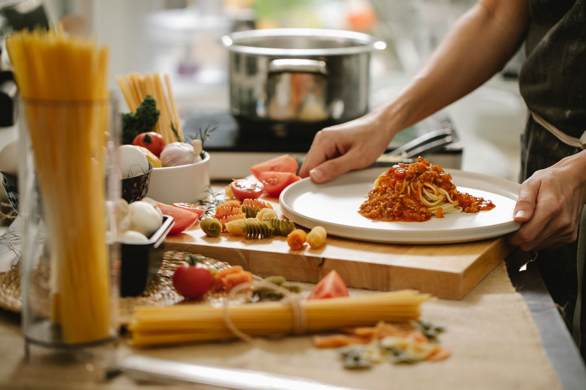 A cook standing at a table with ingredients, preparing a home-cooked meal.